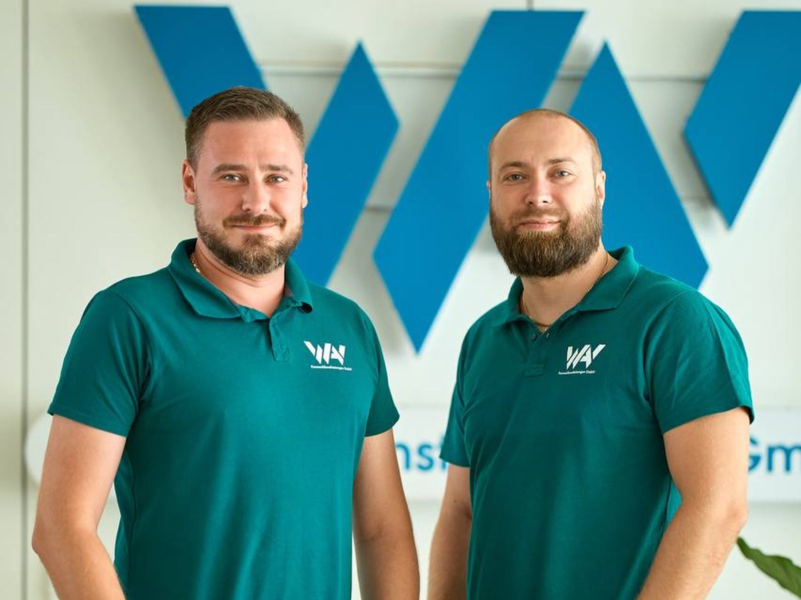 Zwei Mitarbeiter von WAV vor dem Firmenlogo