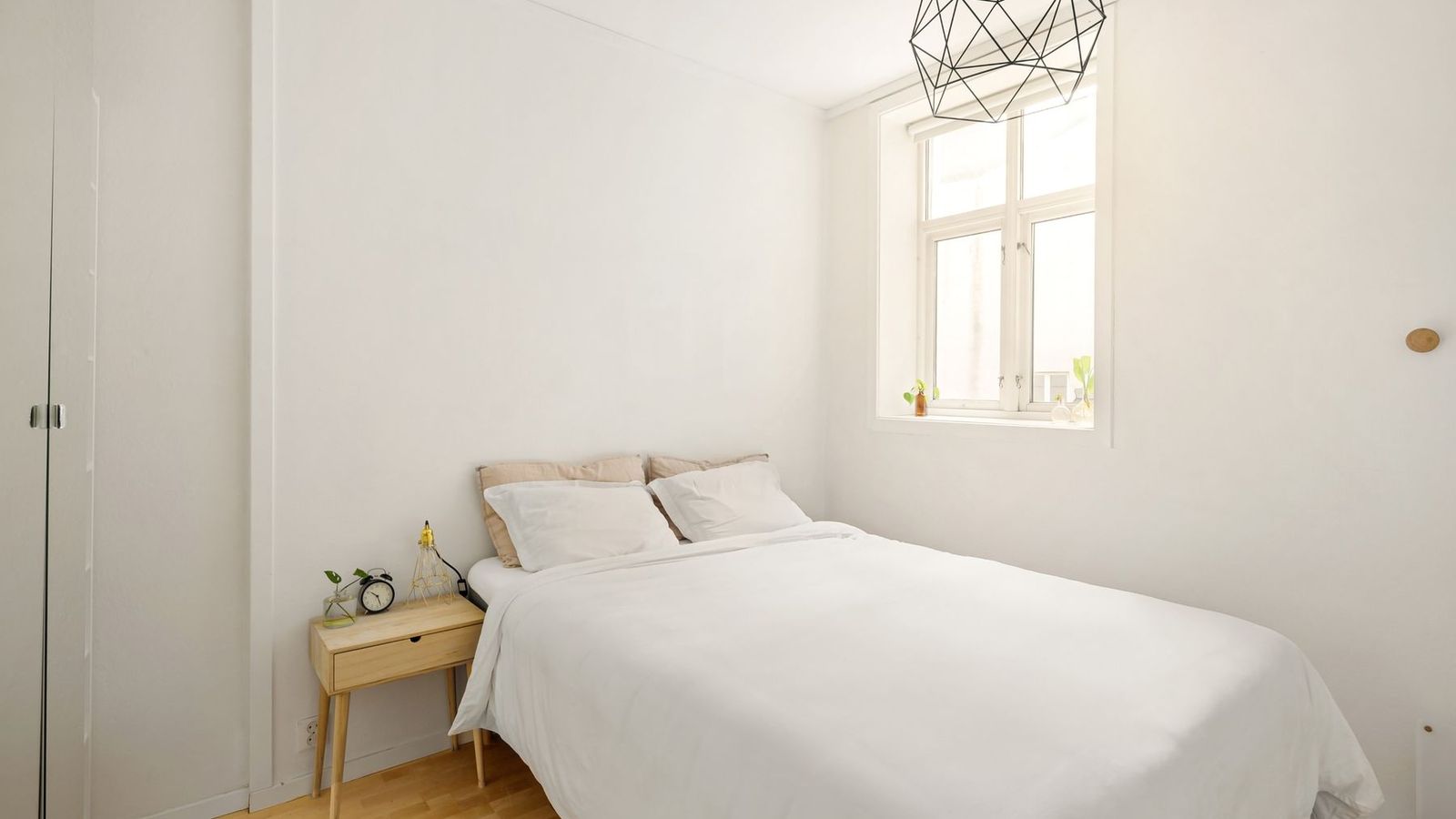 Helles Zimmer mit Bett, Nachttisch und Fenster